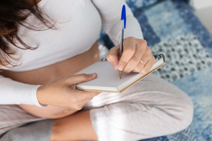 Pregnant woman taking notes in notepad