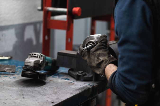 Attentive repairman cutting metal with electric grinder in workshop