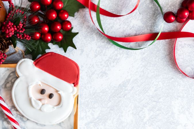 Santa Cookie on a grey backdrop with Christmas decorations.