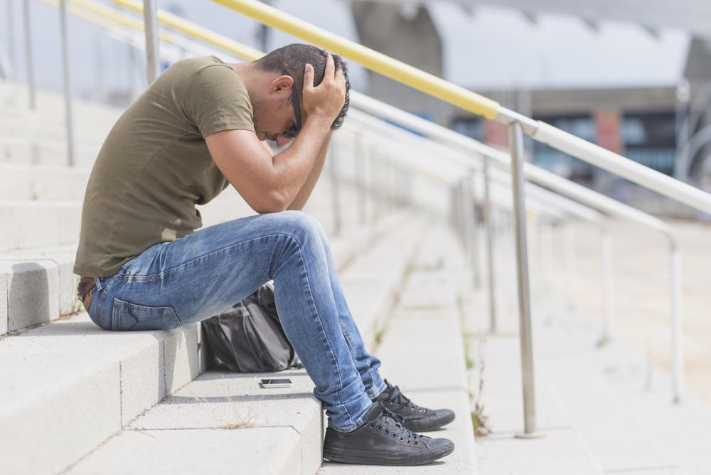 Side view of male sitting on stairs with head in hands