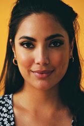 Headshot of Hispanic woman looking at camera in yellow room, vertical