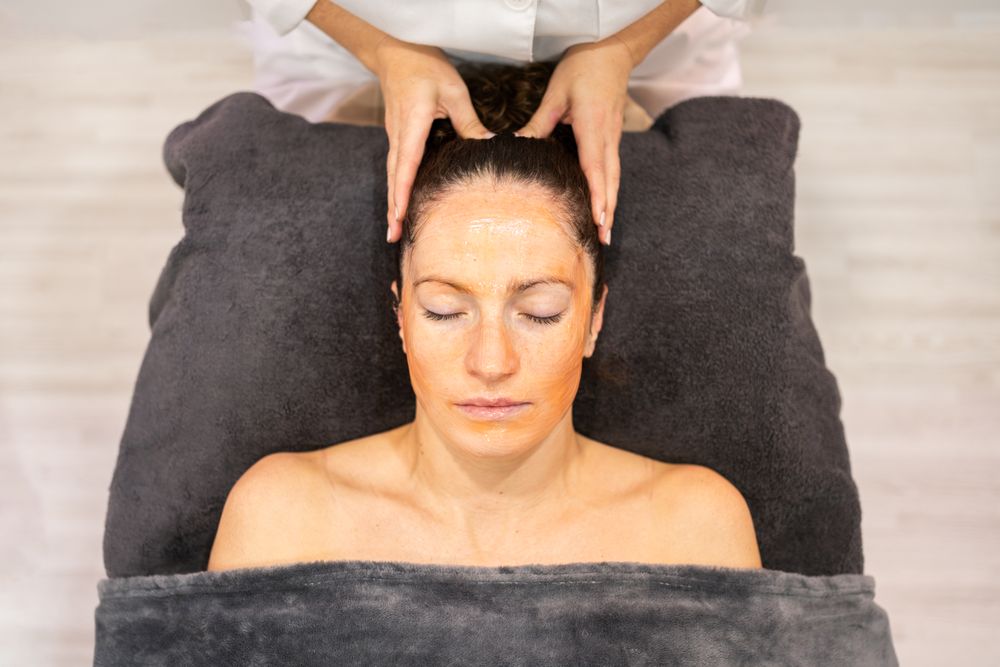 Young woman with cosmetic mask on face lying in beauty center