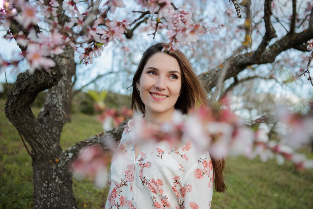 Young happy woman between trees in garden