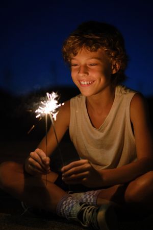 Boy with burning Bengal lights at night