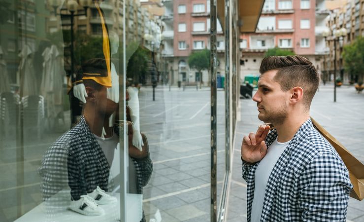 Side view of man looking at the showcase of a store