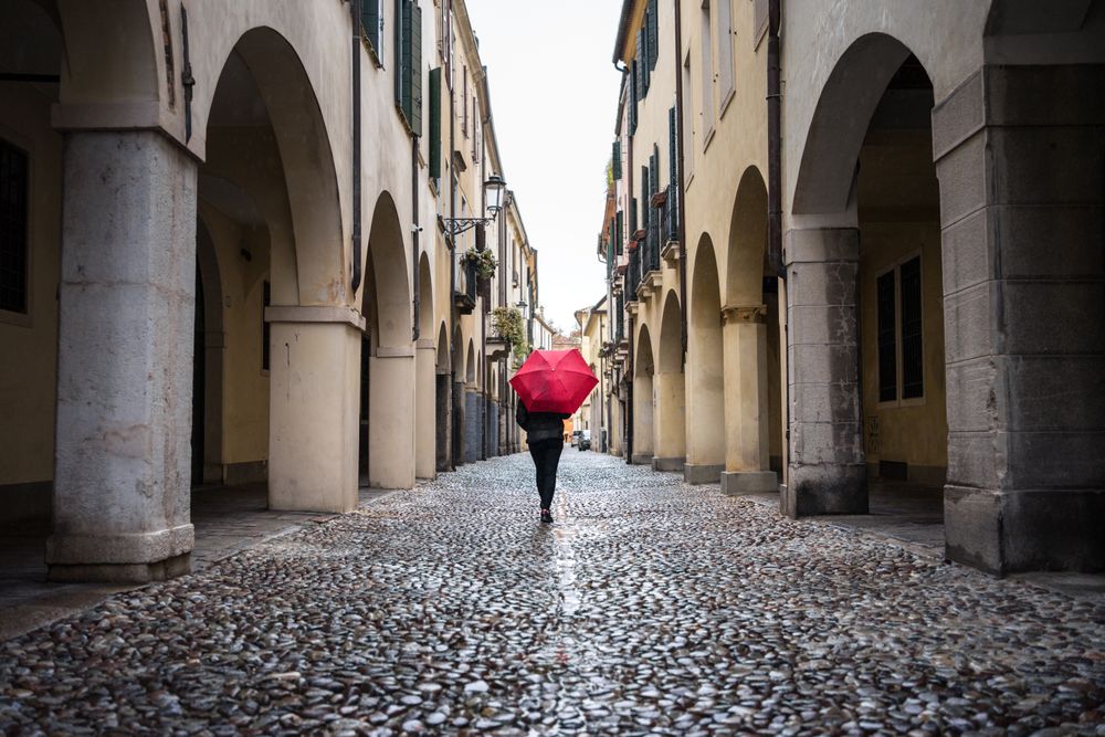 Tourist with umbrella walking at city street on rainy weather