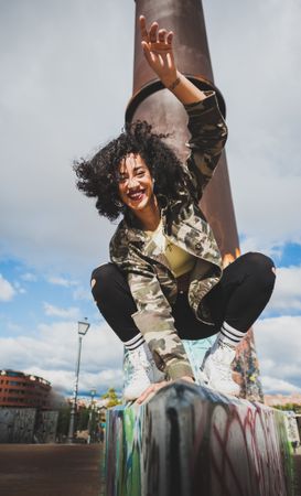 Cheerful sportive woman on fence on street