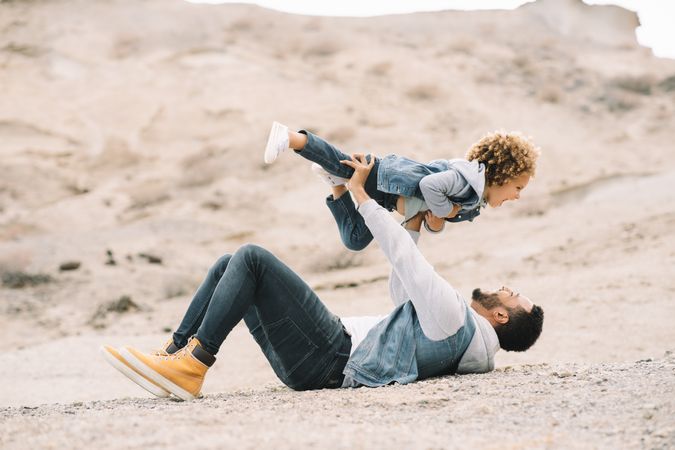 Black father playing with child on ground