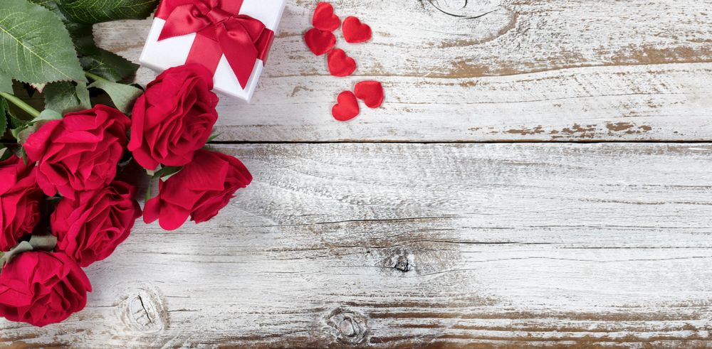 Gift box with red roses and hearts on wood