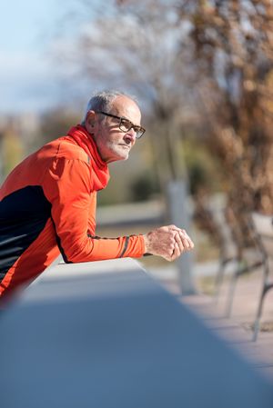 Older male leaning on cement wall in park