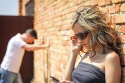Angry woman looking phone and frustrated man on background