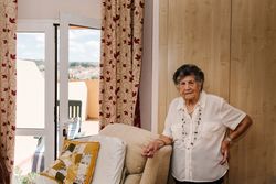 Older woman standing near armchair at home