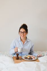 Young woman with breakfast on bed using smart phone