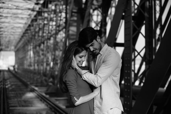 Amorous couple bonding on railway under bridge