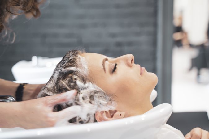 Stylist washing hairs to young woman