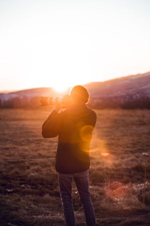 Man shooting on camera beautiful landscape between hills
