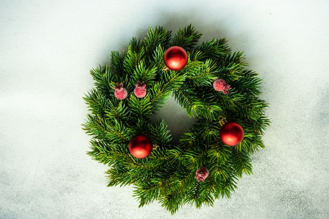 Christmas wreath with red baubles and berries on marble counter