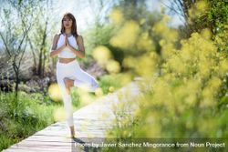 Female wearing light sport clothes in tree pose bxBdr5