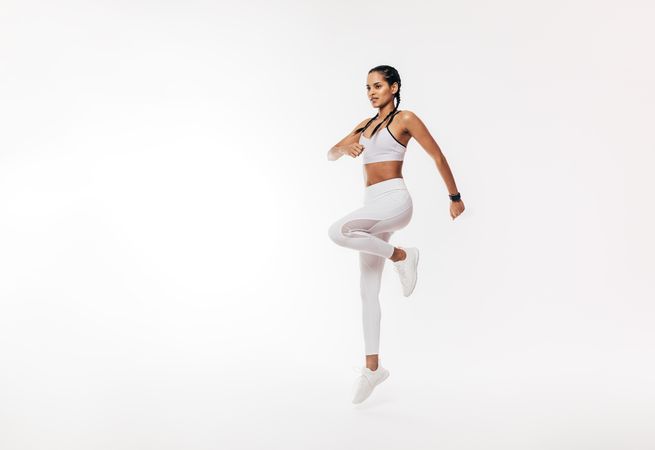 Young fit woman exercising over bright background