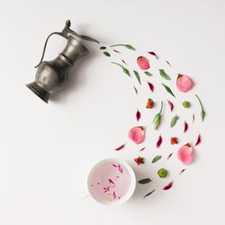 Tea pot pouring various natural herbs with cup of herbal water