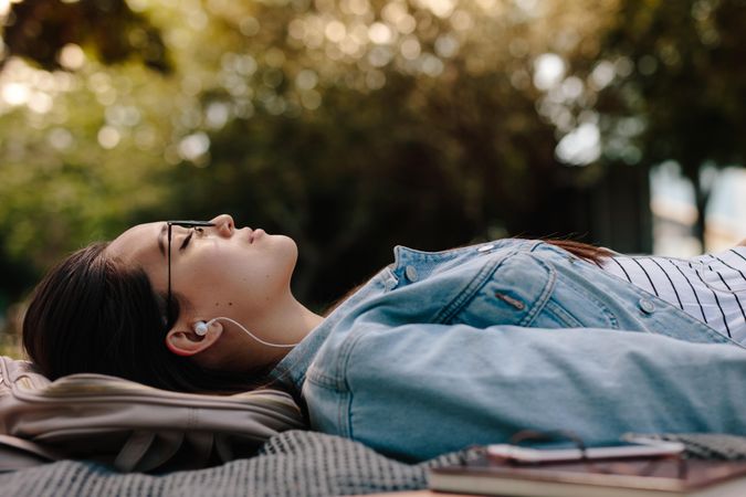 Close up of a woman sleeping in a park listening to music
