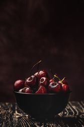 Juicy red cherry in bowl on rustic surface