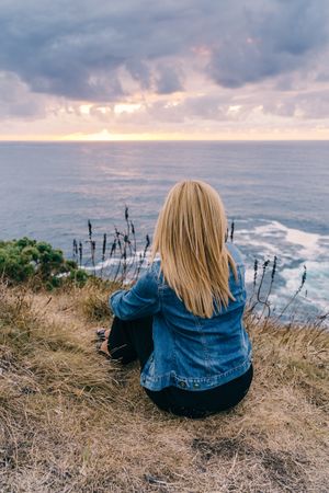 Woman on seashore against dusky clouds