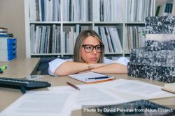 Exhausted woman next to box of documents in office 0PjvY7