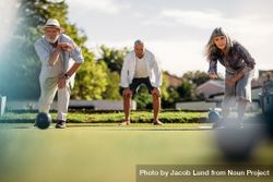 Ground level shot of man and woman playing boules in a lawn with a blurred boules in the foreground bGNqX4
