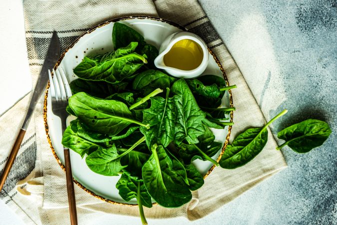 Top view of plate of fresh spinach salad served with oil dressing