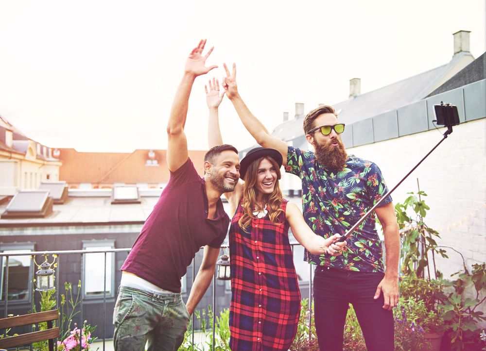 Three people with hands up taking a selfie outside