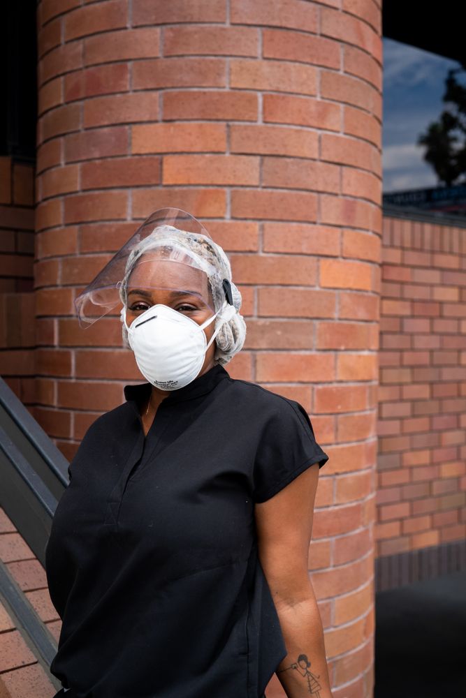 Nurse stands casually outside of medical building smiling and looking at camera