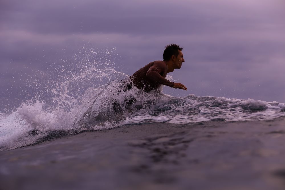 Man on surf board floating on water and cloudy sky