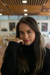 Woman sitting along bookshelves and looking at camera