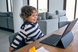 Cute boy watching cartoon on tablet in living room