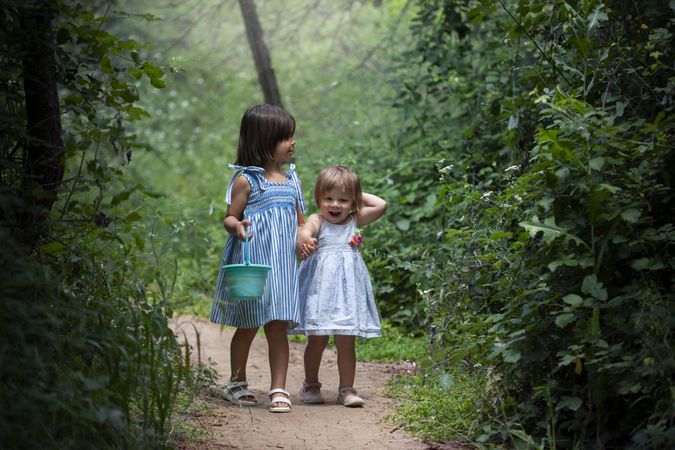 Two girls in dresses walking between trees