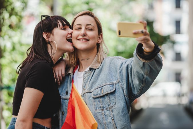 Happy lesbian couple taking selfie on street