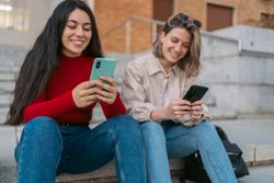 two student sitting on the stairs watching the mobile