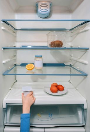 Girl hand taking the last yogurt from the fridge