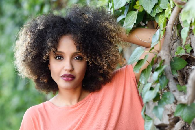 Portrait of beautiful Black woman with afro hairstyle in front of wall with vines