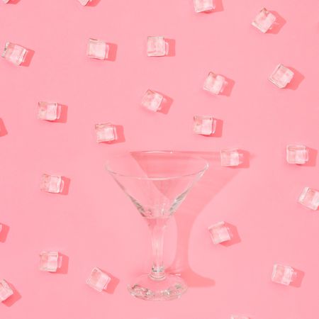 Martini glass with ice cubes pattern on pastel pink background