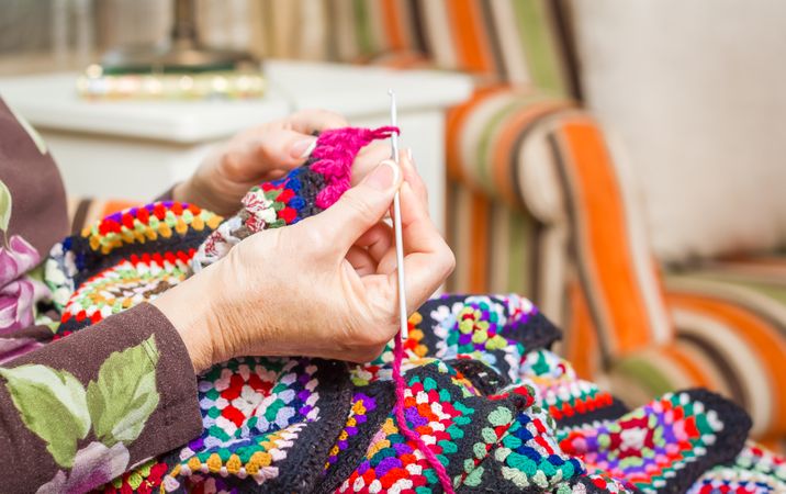 Hands of woman knitting a vintage wool quilt
