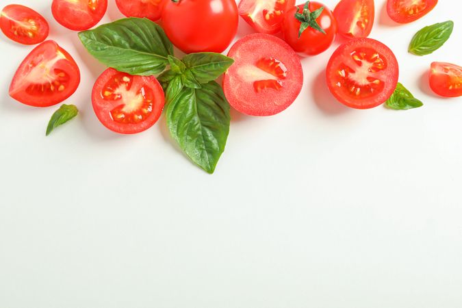 Flat lay composition with fresh cherry tomatoes and basil on light background, space for text. Ripe vegetables