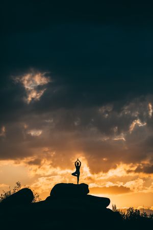 silhouette of woman doing yoga poses outdoors on a amazing sunset