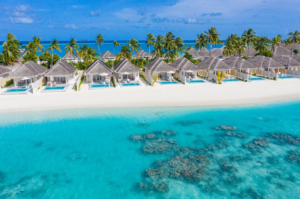Holiday villas line the beach in the Maldives, with copy space