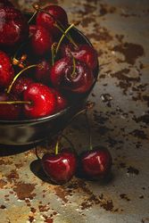 Juicy red cherry in bowl on rustic surface