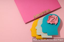Paper cut outs of colorful head on pink background with the word “Amnesia” with copy space 4O63o5