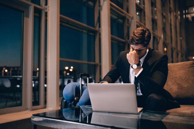 Tired businessman waiting for delayed flight in airport lounge