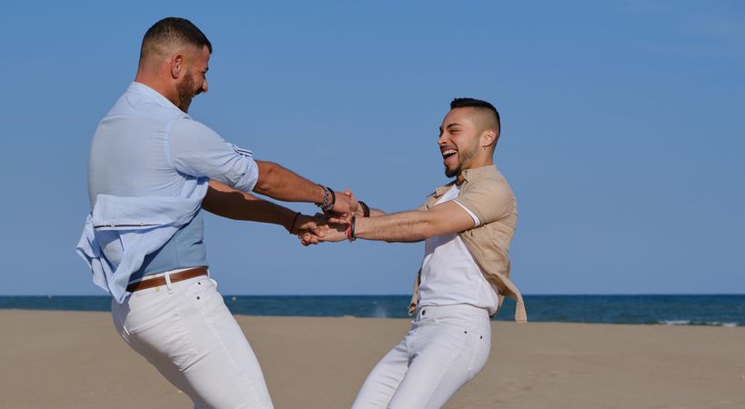 Happy gay couple having fun on beach