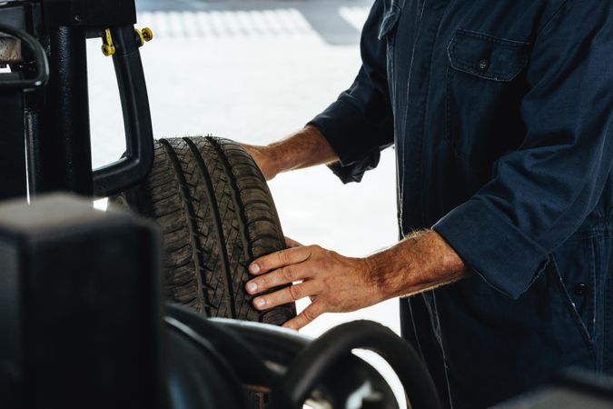 Man examining the wear and tear of car tire in garage